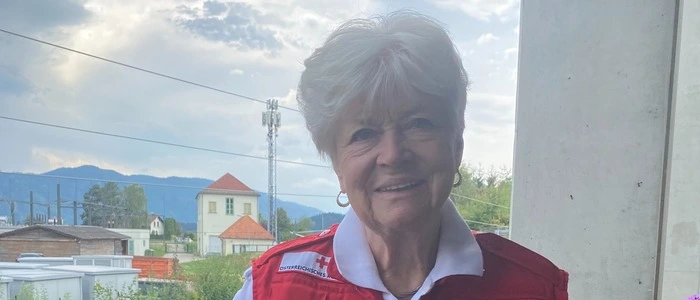 Renate Huber steht in der Rotkreuz-Jacke auf dem Balkon ihrer Wohnung