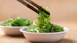 Wakame seaweed salad with sesame seed in a bowl with chopsticks
