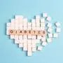 Broken heart made of sugar cubes with inscription diabetes on a blue background. World diabetes day concept.