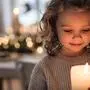 Portrait of cheerful small girl indoors at home at Christmas, holding candle.