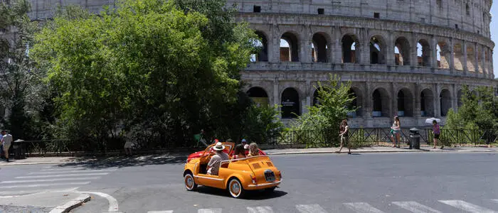 Touristen in einem Fiat 500 „Spiaggina“ vor dem Kolosseum in Rom
