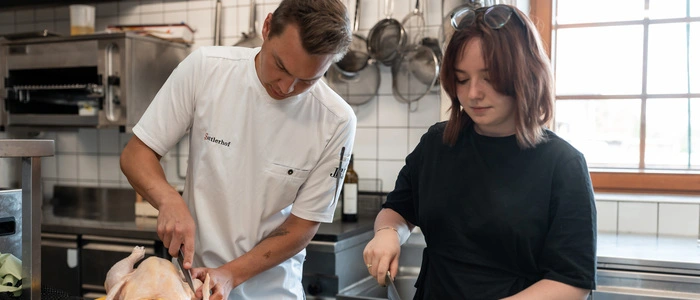 Haubenkoch Markus Sattler zerlegt den Hahn, die Autorin schneidet Pilze und Zwiebeln für die Sauce