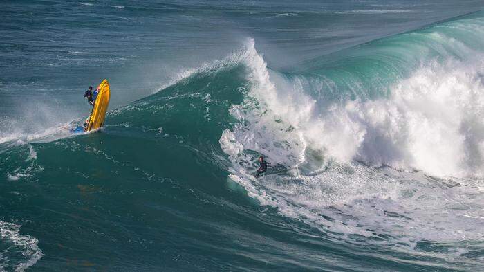 Ein Jetski-Fahrer und ein Surfer auf einer überschlagenden Welle