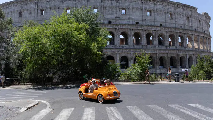 Touristen in einem Fiat 500 „Spiaggina“ vor dem Kolosseum in Rom