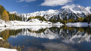 Bei Windstille spiegeln sich die schneebedeckten Berge im Wasser des Duisitzkarsees
