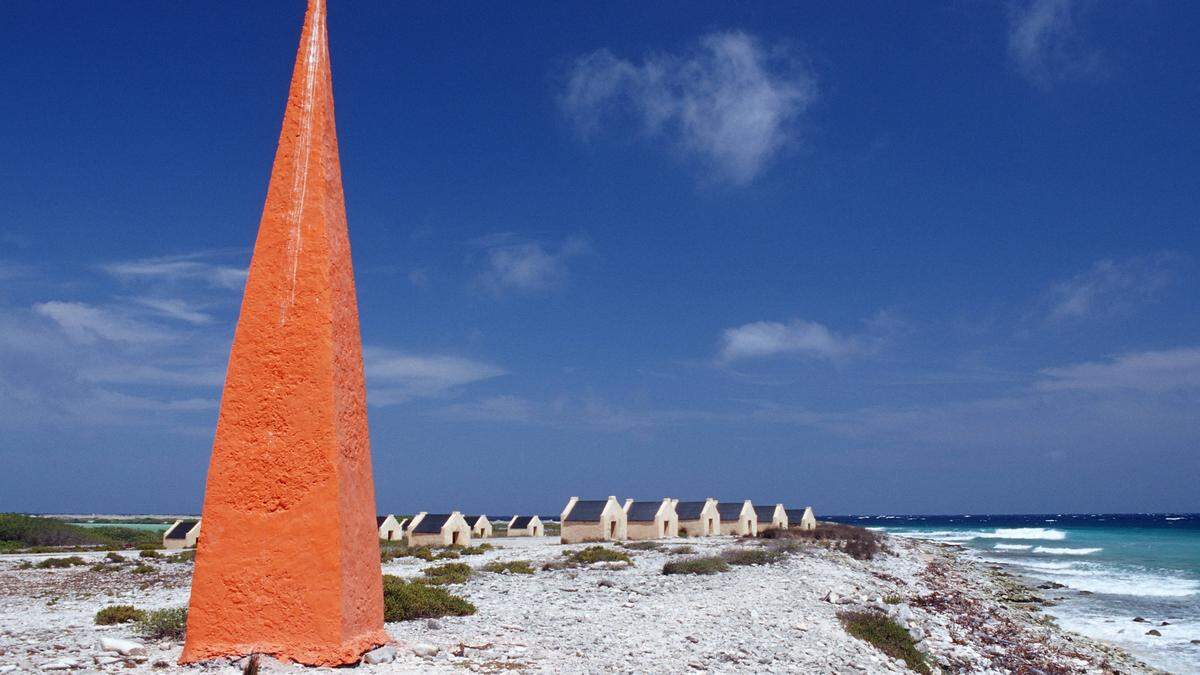 Ehemalige Sklavenhütten an der Küste von Bonaire. Der rote Obelisk diente Kapitänen als Orientierung