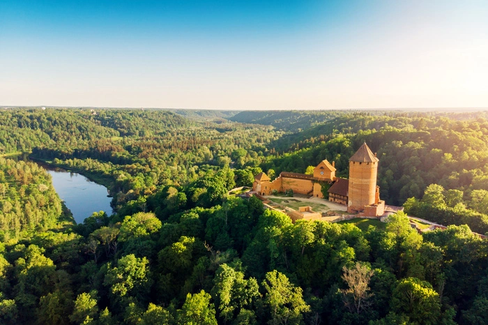 Nationalpark Gauja. Der älteste und größte Nationalpark Lettlands hat seinen Namen vom Fluss Gauja, der die Landschaft prägt. Genauso wie die steilen Klippen wie die von Ērgļu, Höhlen wie die der Lielā Ellīte und leuchtend rote und gelbe Sandsteinfelsen wie der Zvārtes. Ebenfalls rot erheben sich die Türme der mittelalterlichen Burg Turaida über die sattgrünen Baumspitzen. Sie ist eine von mehreren Festungen und Schlössern, die in und um die Städte Cēsis und Sigulda liegen. Das Gebiet, das auch als lettische Schweiz bezeichnet wird, ist ein Paradies für Outdoorfans wie Wanderer, Paddler und Radfahrer.