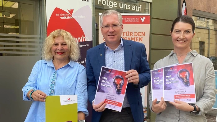 VHS-Geschäftsführerin Beate Gfrerer, Bürgermeister Martin Kulmer, Bezirksstellenkoordinatorin Martina Mittweg stehen vor dem Eingang der VHS in St. Veit und halten Prospekte in der Hand