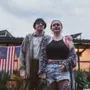 Mann und Frau vor einer Wellblechhütte mit USA-Flaggen