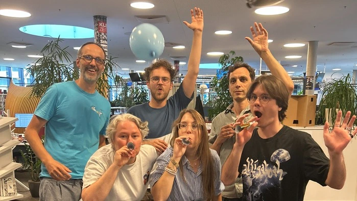 Ein Foto von Graz- und Social-Media-Redakteur*innen, im Newsroom jubelnd mit Tröten und Luftballons
