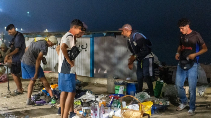 Migrants display clothes, food, and other items laid out on the ground for sale as they spend the night on El Trampolin beach in Ceuta on September 1, 2026. Spain's interior minister has asked police to check a report that a government agency blamed Moroccan security forces for July's mass entry of migrants to the enclave of Ceuta, ministry sources said on September 2, 2026. Spanish Prime Minister Pedro Sanchez said on August 31, 2026 that Morocco was not responsible -- accusing Israel, Russia and the far right of spreading disinformation about the mass entry of around 70,000 migrants into Ceuta. (Photo by Antonio Sempere / AFP)