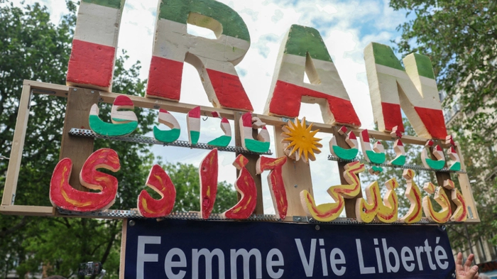 A placard reading "Iran Woman Life Freedom" is seen during a May Day rally marking International Workers' Day in Paris, on May 1, 2026. (Photo by ALAIN JOCARD / AFP)