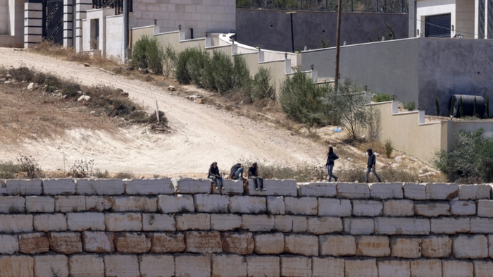 Israeli settlers gather in front of Palestinian houses in the village of Qusra, south of Nablus, in the occupied West Bank, on August 13, 2026. Israel has occupied the West Bank since 1967. More than 500,000 Israelis live in settlements in the territory, which are illegal under international law, among some three million Palestinians. Violence against Palestinians by Israeli settlers has increased dramatically since the October 7, 2023 attack on Israel by Hamas from the Gaza Strip. (Photo by Zain JAAFAR / AFP)
