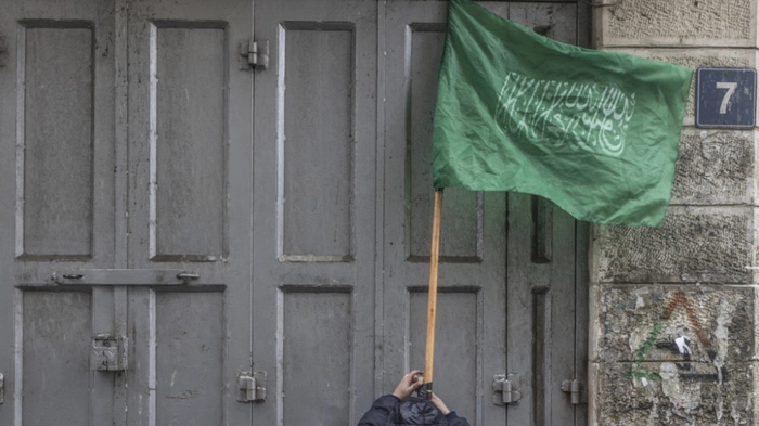 A child tapes a stick holding a Hamas flag during a demonstration in support of the Palestinian resistance in Al-Manara Square in the West Bank city of Ramallah, on January 12, 2024. (Photo by MARCO LONGARI / AFP)