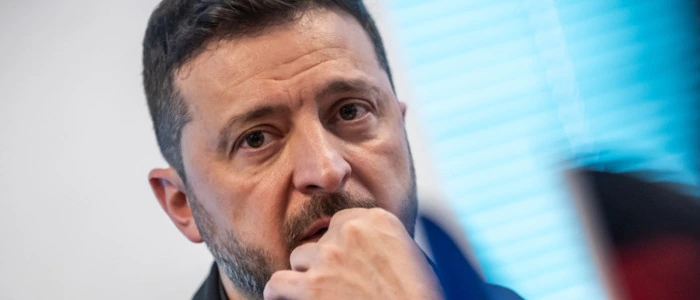 Ukraines Präsident Wolodymyr Selenskyj hält die linke Hand vor seinen Mund.