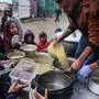 Volunteers distribute rations of red lentil soup to displaced Palestinians in Rafah in the southern Gaza Strip on February 18, 2024, amid the ongoing conflict between Israel and the militant group Hamas. After more than four months of war that has flattened huge swathes of the Strip, Gazans are inching closer towards famine, according to the UN's World Food Programme. (Photo by SAID KHATIB / AFP)