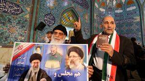 Ein Mann hält ein Poster mit einem Bild von Ayatollah Ali Khamenei. Der oberste geistliche Führer des Irans hatte nachdringlich an die Bevölkerung appelliert, an der Wahl teilzunehmen.