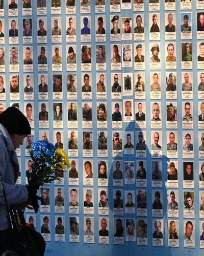 Eine Frau legt Blumen für die gefallenen Soldaten an der „Mauer der Erinnerung“ in Kiew ab.