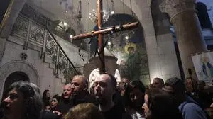Worshippers carry a wooden cross the Holy Sepulchre church during the Holy Friday procession through the Via Dolorosa (Way of Suffering)in Jerusalem's Old City on March 29, 2024. (Photo by GIL COHEN-MAGEN / AFP)