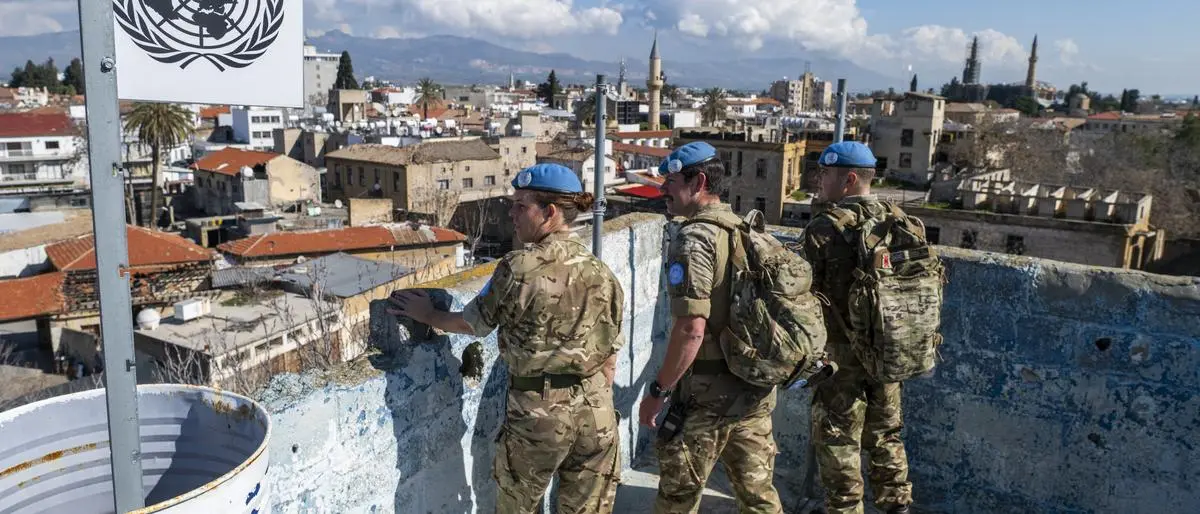 Sappers Sam Proctor (R), Aaron Joyce and Corporal Anna Rowell from the British Army's 71 Engineer Regiment, members of the United Nations Peacekeeping Force in Cyprus (UNFICYP), climb up on a rooftop of an abandoned building while patroling along the buffer zone, which separates the internationally recognized Republic of Cyprus and the breakaway Turkish Republic of Northern Cyprus (TRNC)recognized only by Ankarain the divided capital Nicosia on February 21, 2024. EU member Cyprus has been divided since 1974 when Turkish forces occupied the island's northern third in response to a military coup sponsored by the junta then in power in Greece. (Photo by Jewel SAMAD / AFP)