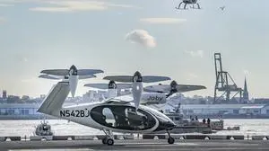 The Volocopter 2X, an electric vertical takeoff and landing (eVTOL) aircraft, flies above the Joby eVTOL aircraft, during a demonstration of eVTOLs in a test flight, Monday, Nov. 13, 2023, in New York at Manhattan's downtown heliport. (AP Photo/Bebeto Matthews)