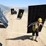 (FILES) Workers carry solar panels to be installed in the desert at the Ningguoyun Lingwu 1 million kilowatt photovoltaic project in Lingwu, in Chinas northern Ningxia region on April 14, 2025. Call it the China power paradox: as Beijing installs renewable energy at a rate that far outpaces the entire rest of the world, its new coal plant projects are also booming. (Photo by AFP) / China OUT / TO GO WITH China-energy-coal-climate-environment ,FOCUS by Sara HUSSEIN