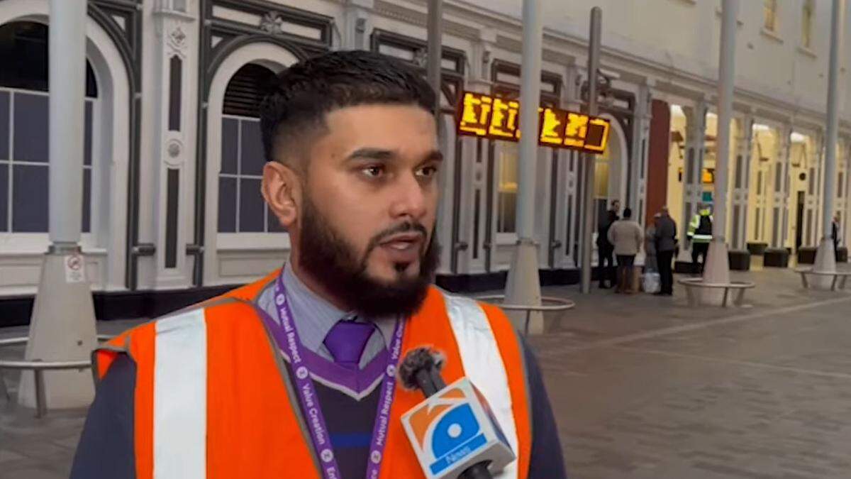 Rizwan Javed (33) spricht in einem Bahnhof Warnweste gekleidet in das Mikrofon eines TV-Reporters. | Rizwan Javed will die Berichterstattung nutzen, um auf die Wichtigkeit mentaler Gesundheit aufmerksam zu machen 