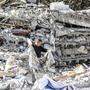 Ein Mann durchsucht die Trümmer eines völlig zerstörten Hauses  | Die Stadt Adiyaman wurde schwer getroffen von dem Erdbeben im letzten Februar 