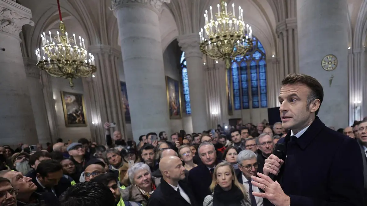 Attendees including workers of reconstruction of Notre-Dame de Paris cathedral gather during a speech by French President Emmanuel Macron (C) in the nave of the cathedral in Paris, on November 29, 2024. The Notre-Dame Cathedral is set to re-open early December 2024, with a planned weekend of ceremonies on December 7 and 8, 2024, five years after the 2019 fire which ravaged the world heritage landmark and toppled its spire. (Photo by Christophe PETIT TESSON / POOL / AFP)