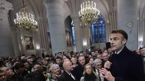 Attendees including workers of reconstruction of Notre-Dame de Paris cathedral gather during a speech by French President Emmanuel Macron (C) in the nave of the cathedral in Paris, on November 29, 2024. The Notre-Dame Cathedral is set to re-open early December 2024, with a planned weekend of ceremonies on December 7 and 8, 2024, five years after the 2019 fire which ravaged the world heritage landmark and toppled its spire. (Photo by Christophe PETIT TESSON / POOL / AFP)
