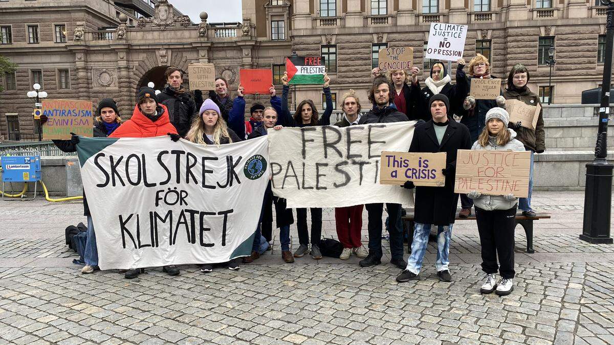 Eine kleine Gruppe Menschen mit Greta Thunberg. Viele halten Plakate hoch, auf denen unter anderem „Free Palestine“ zu lesen ist.   | Gemeinsam mit Mitstreitern bekundete die 20-jährige Klimaaktivistin erneut Solodarität mit den Palästinensern. 