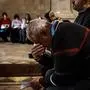 BETHLEHEM, OCCUPIED WEST BANK -- DECEMBER 14, 2023: Daher Nassar lowers his head to pray during a Christmas carol event as they sing in front of a Christmas nativity scene with a the symbolic Baby Jesus in a manger of rubble and destruction to reflect the reality of Palestinian children living and being born today, at the Evangelical Lutheran Christmas Church in Bethlehem, Occupied West Bank , Thursday, Dec. 14, 2023. Palestinian Christians are marking a somber Christmas this year, canceling festivities in solidarity with suffering in the Gaza Strip as the war between Israel and Hamas grinds on. In Bethlehem, the West Bank town revered by Christians as the place of Jesus' birth, prayers, church services and the annual procession of Christian patriarchs will go on as usual, but more joyous holiday trappings have gone by the wayside: no twinkling Christmas lights, no elaborately decorated tree in Manger Square, no parade with marching bands. "How could we celebrate?" asked the town's mayor. (MARCUS YAM / LOS ANGELES TIMES)