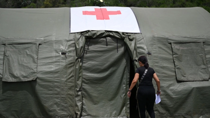 A woman enters a tent at Brazil's military field hospital in Camuri Chico, near Macuto, La Guaira State, Venezuela on July 9, 2026, following the June 24 twin earthquakes. The United Nations launched an urgent appeal on July 8, 2026 for nearly $300 million towards Venezuela earthquake relief operations as the death toll from the disaster rose to more than 3,800 people. (Photo by Raul ARBOLEDA / AFP)