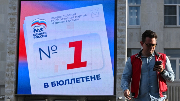 A man walks past a digital screen on the building of the United Russia party's headquarters calling people to vote for the party's candidates in the upcoming election for Russia's lower house of parliament, the State Duma, in Moscow on September 15, 2026. The 2026 parliamentary election will be held over a three-day period from September 18 to 20. (Photo by Igor IVANKO / AFP)