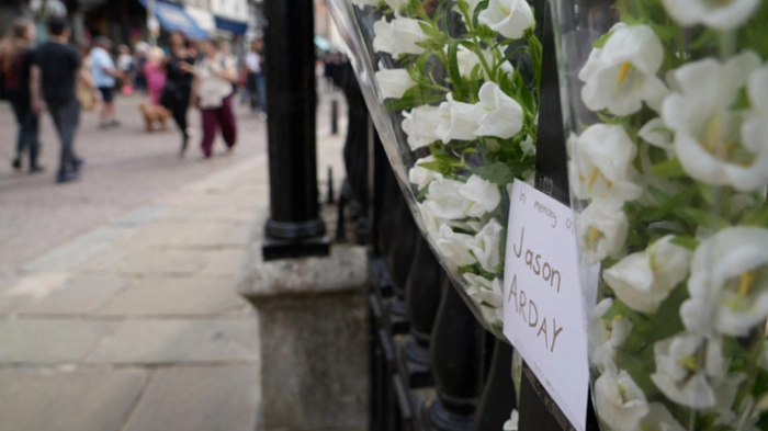 Members of the public walk past floral tributes to remember academic Jason Arday, attached to the railings outside Senate House in the University of Cambridge in Cambridge, eastern England on August 15, 2026. Cambridge's top administrator Vice-Chancellor Deborah Prentice said Friday the UK university was "desperately saddened" by the death of Jason Arday, an academic who quit the prestigious institution last week amid a plagiarism scandal. (Photo by Justine GERARDY / AFP)