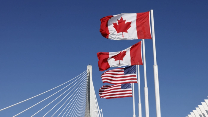 Flags of Canada and United States fly across the international border on the Gordie Howe International bridge that connects Windsor, Ontario, Canada and Detroit, Michigan on September 6, 2026. Canada announced on August 25, 2026 counter-tariffs on US goods ranging between 15 and 50 percent, intensifying the trade war between the historically close allies. Ottawa's retaliation will take effect September 8, a timeframe earlier outlined by Prime Minister Mark Carney after US President Donald Trump's 50-percent duties came into place August 22, 2026. (Photo by JEFF KOWALSKY / AFP)