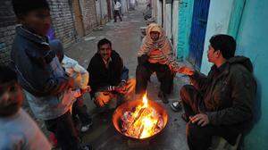 Pakistanische Christen wärmen sich in einem Slum von Islamabad zu Weihnachten an einem Feuer