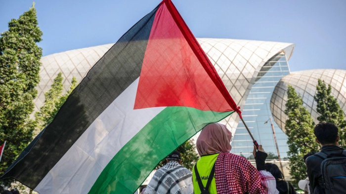 A protester carries a Palestinian flag during a rally condemning US-Israeli attacks on Iran and Israeli attacks on Lebanon and Palestine on the sidelines of the Defence Services Asia (DSA) Exhibition and Conference outside the Malaysia International Trade and Exhibition Centre (MITEC) in Kuala Lumpur on April 20, 2026. (Photo by Mohd Rasfan / AFP)
