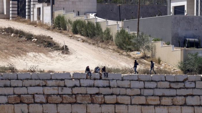 Israeli settlers gather in front of Palestinian houses in the village of Qusra, south of Nablus, in the occupied West Bank, on August 13, 2026. Israel has occupied the West Bank since 1967. More than 500,000 Israelis live in settlements in the territory, which are illegal under international law, among some three million Palestinians. Violence against Palestinians by Israeli settlers has increased dramatically since the October 7, 2023 attack on Israel by Hamas from the Gaza Strip. (Photo by Zain JAAFAR / AFP)