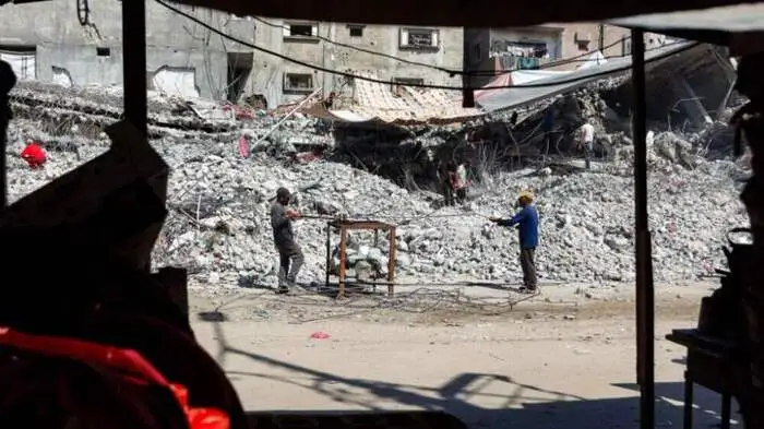TOPSHOT - Salvage workers scrap steel rods from the rubble of a building that was destroyed during Israel's war against Hamas in Gaza, to use the recycled remains in the future, in Gaza City on August 16, 2026. The Palestinian Islamist group Hamas had said on August 15 that it asked the US-backed Board of Peace to "compel" Israel to implement its obligations under the first phase of the US-brokered ceasefire plan in Gaza and to approve the roadmap for its second phase, after its leader met with the US president's envoy Jared Kushner in Egypt. (Photo by Omar AL-QATTAA / AFP)