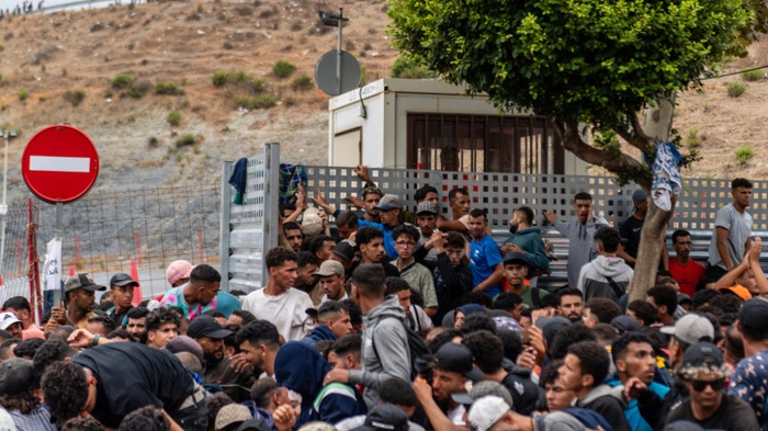 A large group of migrants crowd outside the entrance of the Loma del Colmenar reception center, waiting for admission, in Ceuta on September 1, 2026. Spanish Prime Minister Pedro Sanchez yesterday ruled out Moroccan responsibility in last month's migrant rush to Ceuta, accusing Israel, Russia and the far right of spreading disinformation about the crisis. More than 70,000 migrants entered the small Spanish territory in north Africa on July 30-31, swimming or crossing on foot from neighbouring Morocco in an unprecedented rush that left scores dead. (Photo by Antonio Sempere / AFP)