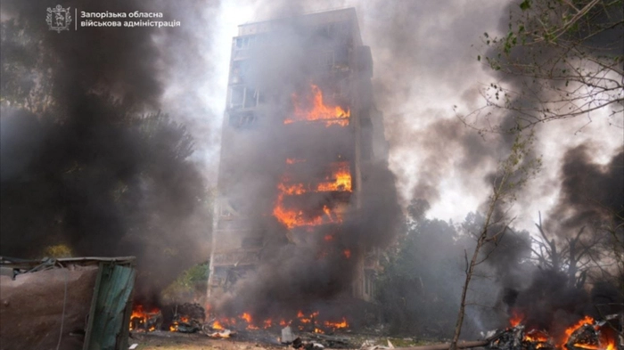 This handout photograph taken and released on July 21, 2026, from the official Telegram channel of the Zaporizhzhia Regional Military Administration, shows Ukrainian firefighters working to extinguish a fire in a residential building at the site of an air strike in the town of Zaporizhzhia, amid the Russian invasion of Ukraine. During the day, Russian forces launched guided glide bombs at central Zaporizhzhia. Two local residents were killed and nine others were injured according to Zaporizhzhia military administration. One glide bomb landed near a printing house, setting parked cars on fire. Another bomb struck near a nine-storey apartment building, sparking a fire that engulfed the building. (Photo by Handout / Zaporizhzhia Regional Military Administration / AFP) / RESTRICTED TO EDITORIAL USE - MANDATORY CREDIT "AFP PHOTO / Zaporizhzhia Regional Military Administration" - HANDOUT - NO MARKETING NO ADVERTISING CAMPAIGNS - DISTRIBUTED AS A SERVICE TO CLIENTS