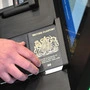 Ein britischer Reisepass wird gescannt, darüber hält eine Person ihre Hand.