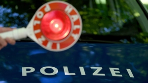 Rote Verkehrskelle vor der Motorhaube eines Polizeiautos