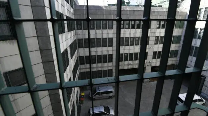 Blick durch Gitterstäbe in einen Innenhof.