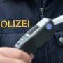 Nahaufnahme eines Alkomaten, im Hintergrund ist die Jacke eines Polizisten mit der Aufschrift Polizei zu sehen