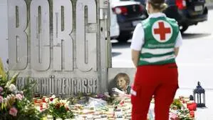 Zahllose Trauerkerzen und Blumen beim Eingang zum Borg Dreischützengasse; eine Rot-Kreuz-Mitarbeiterin steht mit dem Rücken zur Kamera