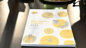 Ein Folder liegt auf einem Tisch, Rassismus-Report 2018 ist darauf zu lesen