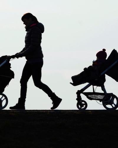 Zwei Kinderwägen, die auf einer Straße geschoben werden. | Kinderarmut ist teuer. Laut OECD kosten deren Folgen Österreich 17 Milliarden Euro pro Jahr.