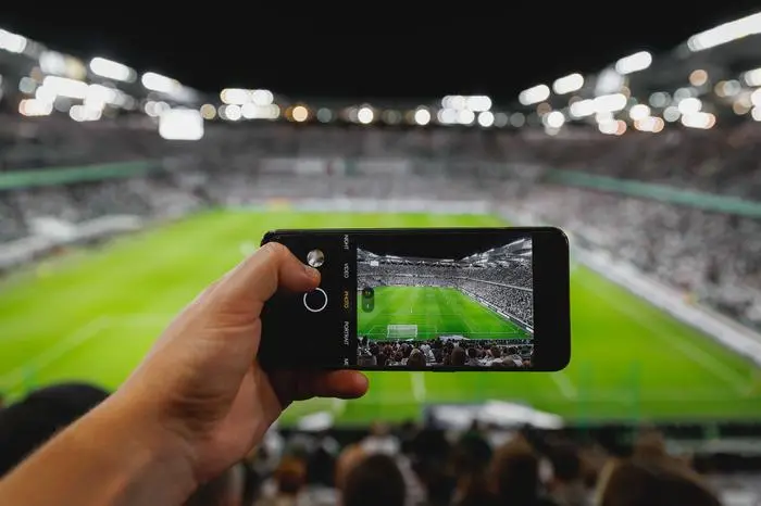 Smartphone photographing football game on the stadium Model Released Property Released xkwx football stadium phone smartphone soccer mobile technology fan game event sport digital live smart online passion camera cell video photo display social spectator recording camp lifestyle cellphone trophy hd data nou hand internet watch photography watching picture europe take selfie 5g field media tablet streaming telephone app people crowd